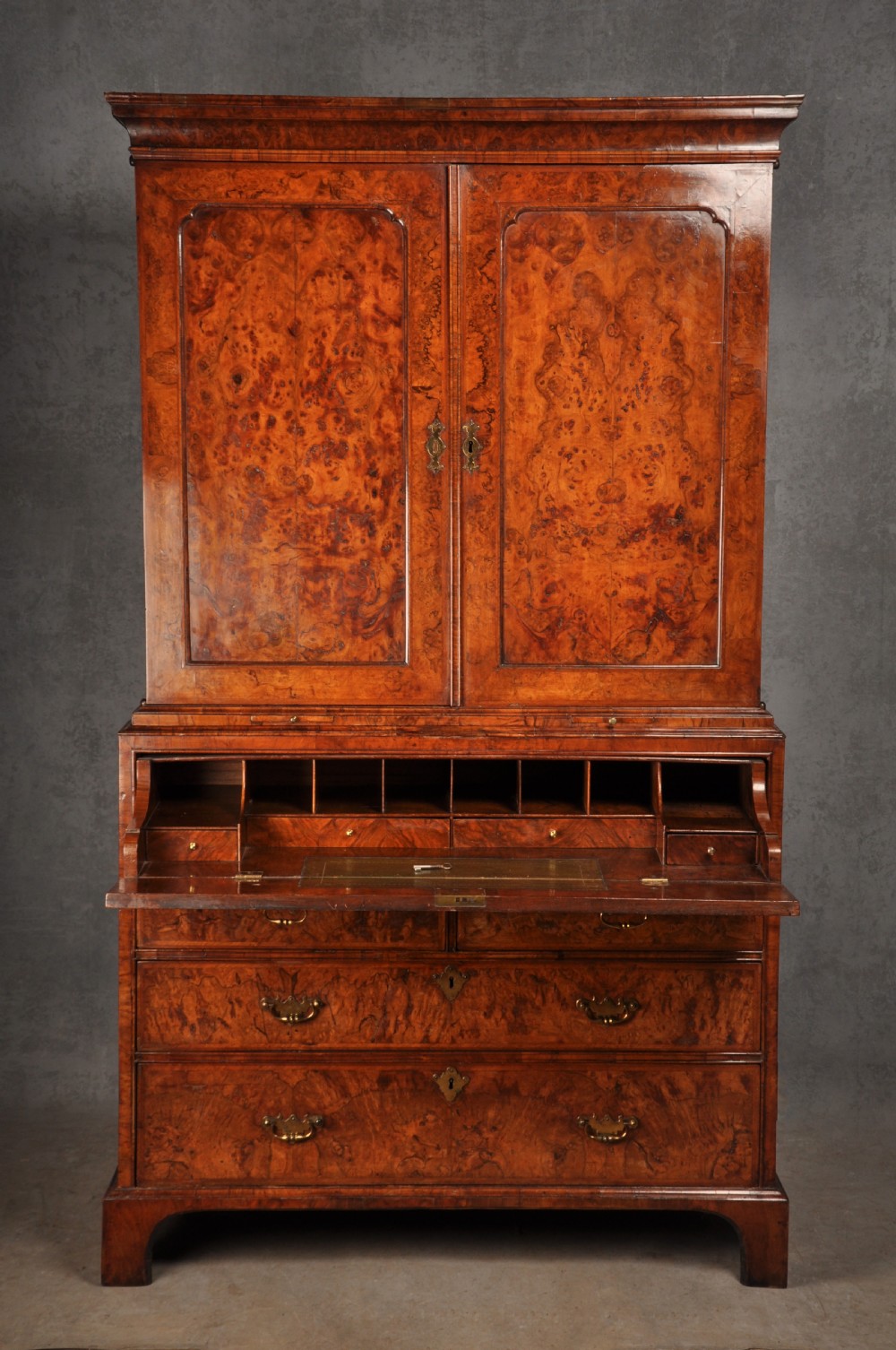 An early eighteenth-century burr walnut secretaire cabinet featuring double upper doors and a lower chest of drawers with brass handles. View IV