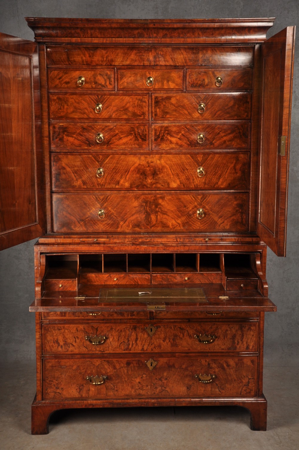 An early eighteenth-century burr walnut secretaire cabinet featuring double upper doors and a lower chest of drawers with brass handles. View V