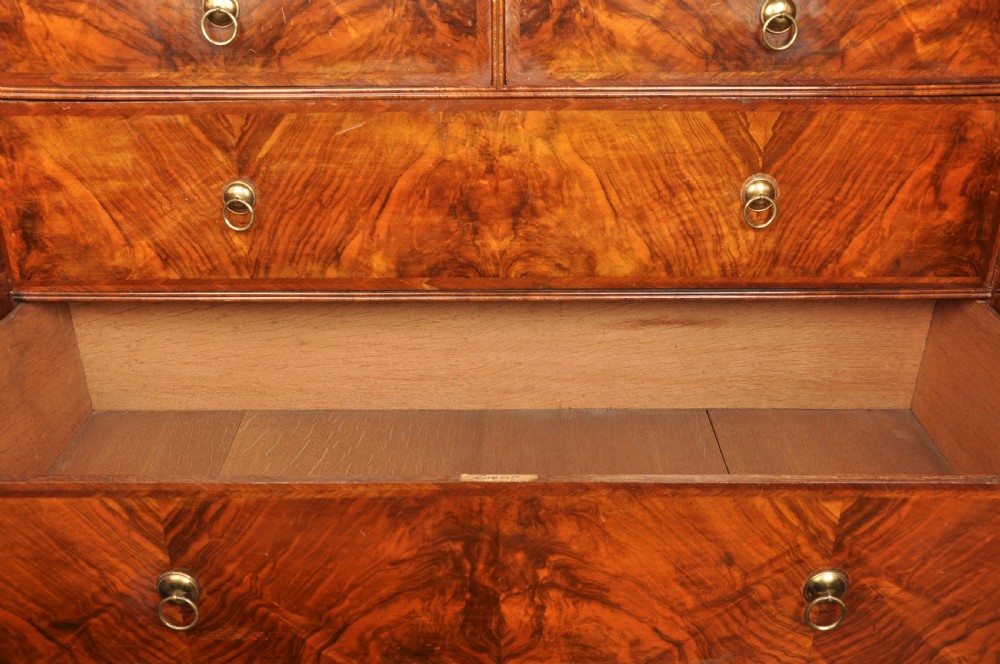 An early eighteenth-century burr walnut secretaire cabinet featuring double upper doors and a lower chest of drawers with brass handles. View XXVI