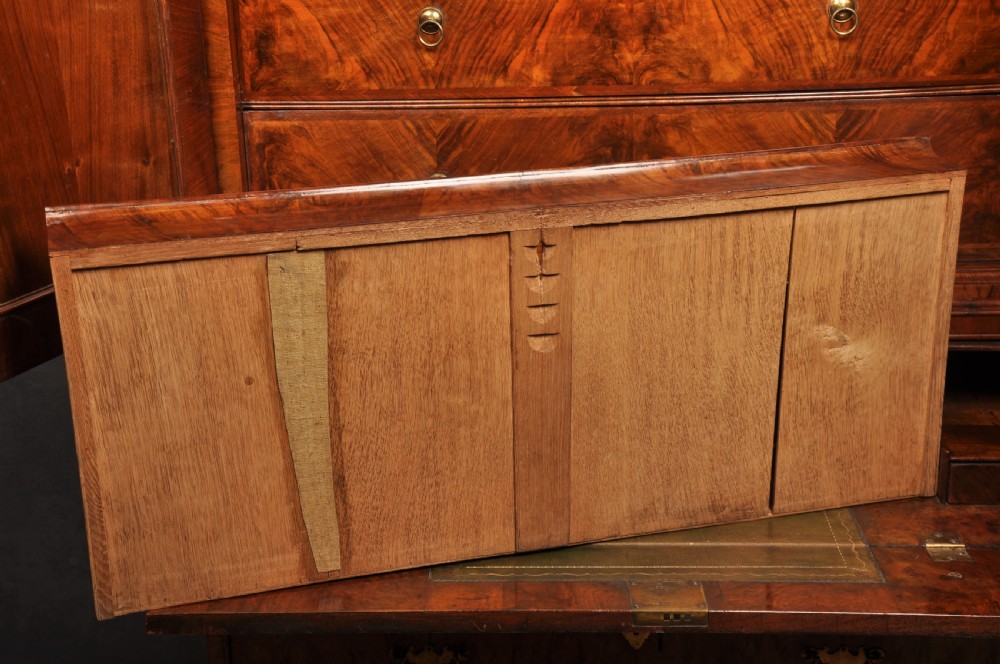An early eighteenth-century burr walnut secretaire cabinet featuring double upper doors and a lower chest of drawers with brass handles. View XXVIII