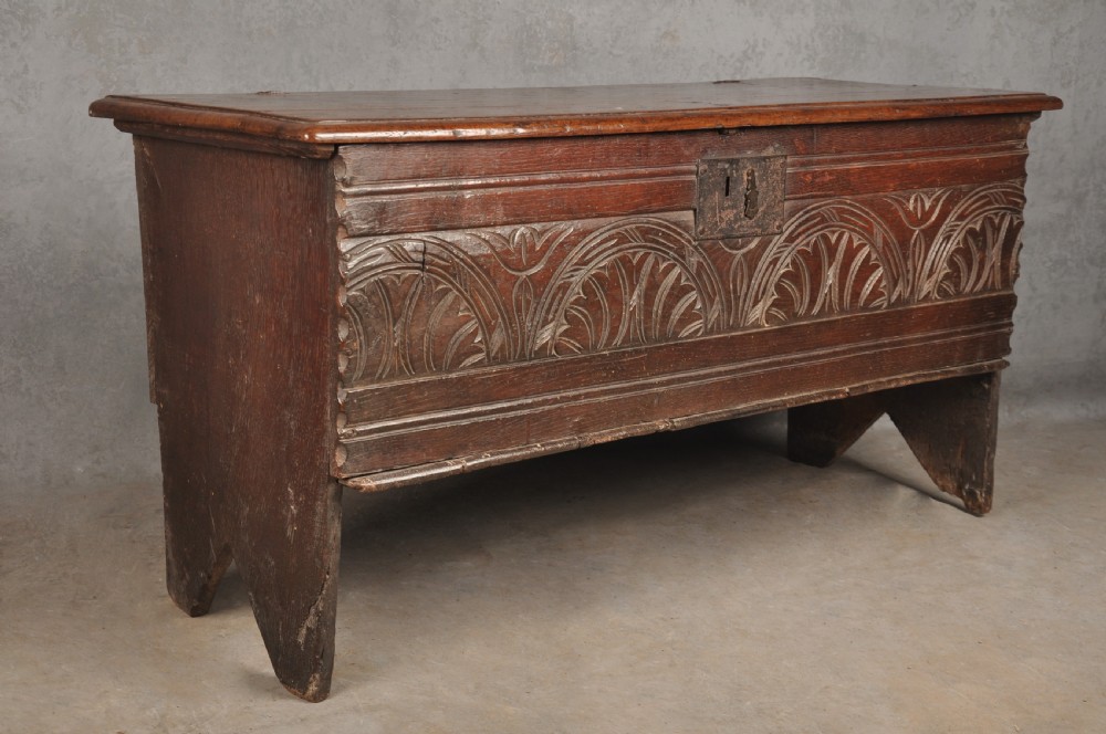A small 17th century dark oak coffer featuring a flat hinged lid, carved lunette motifs across the front panel, and an iron lock plate. View II