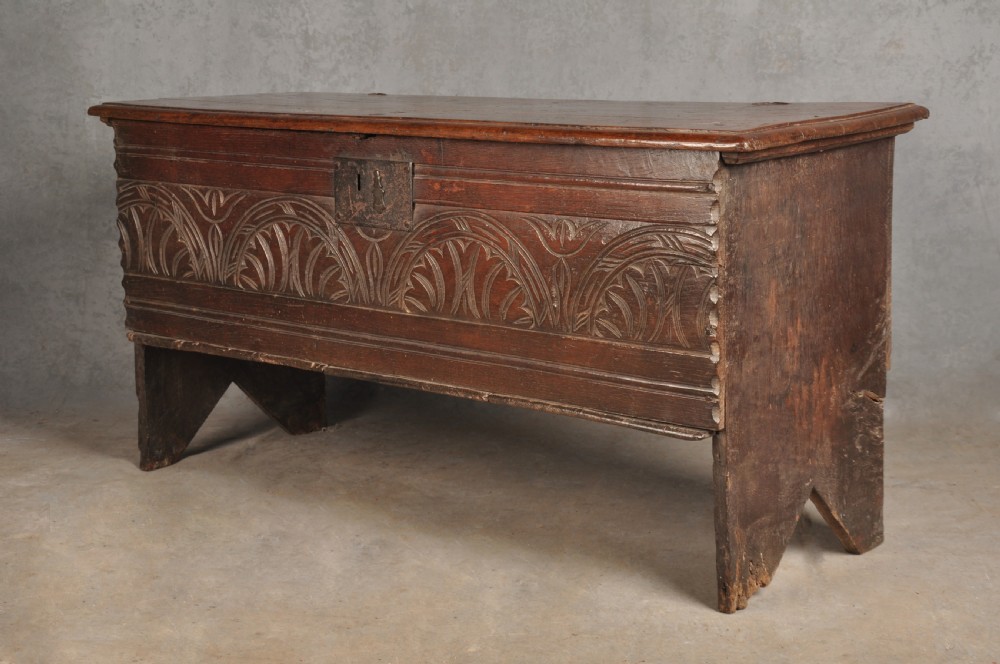 A small 17th century dark oak coffer featuring a flat hinged lid, carved lunette motifs across the front panel, and an iron lock plate. View III