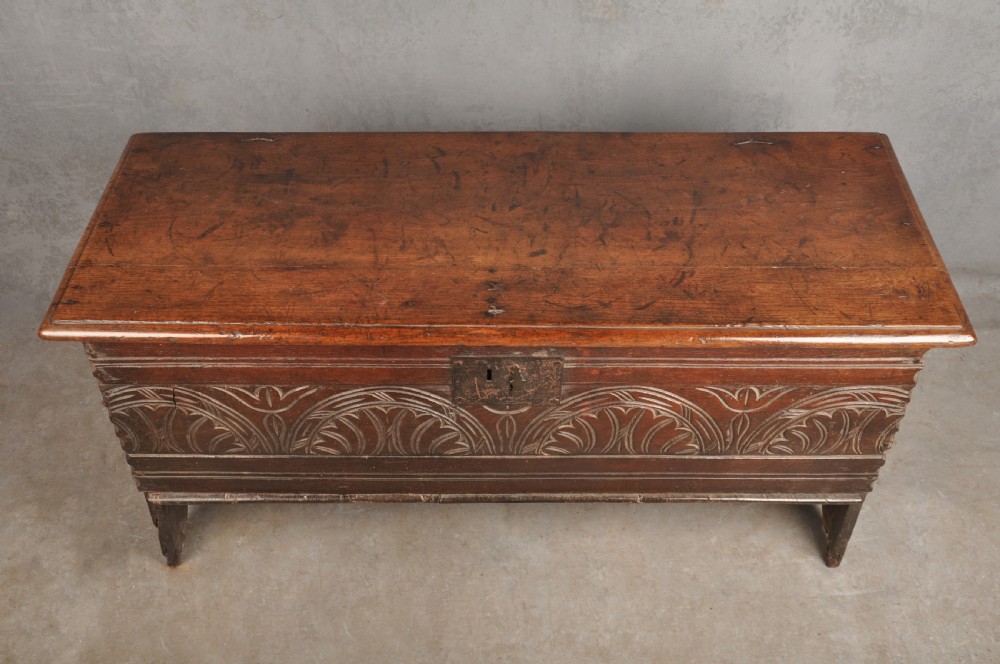 A small 17th century dark oak coffer featuring a flat hinged lid, carved lunette motifs across the front panel, and an iron lock plate. View IV