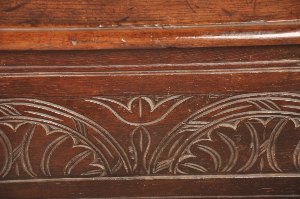 A small 17th century dark oak coffer featuring a flat hinged lid, carved lunette motifs across the front panel, and an iron lock plate. View VIII