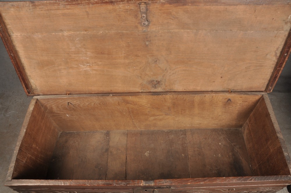 A small 17th century dark oak coffer featuring a flat hinged lid, carved lunette motifs across the front panel, and an iron lock plate. View X