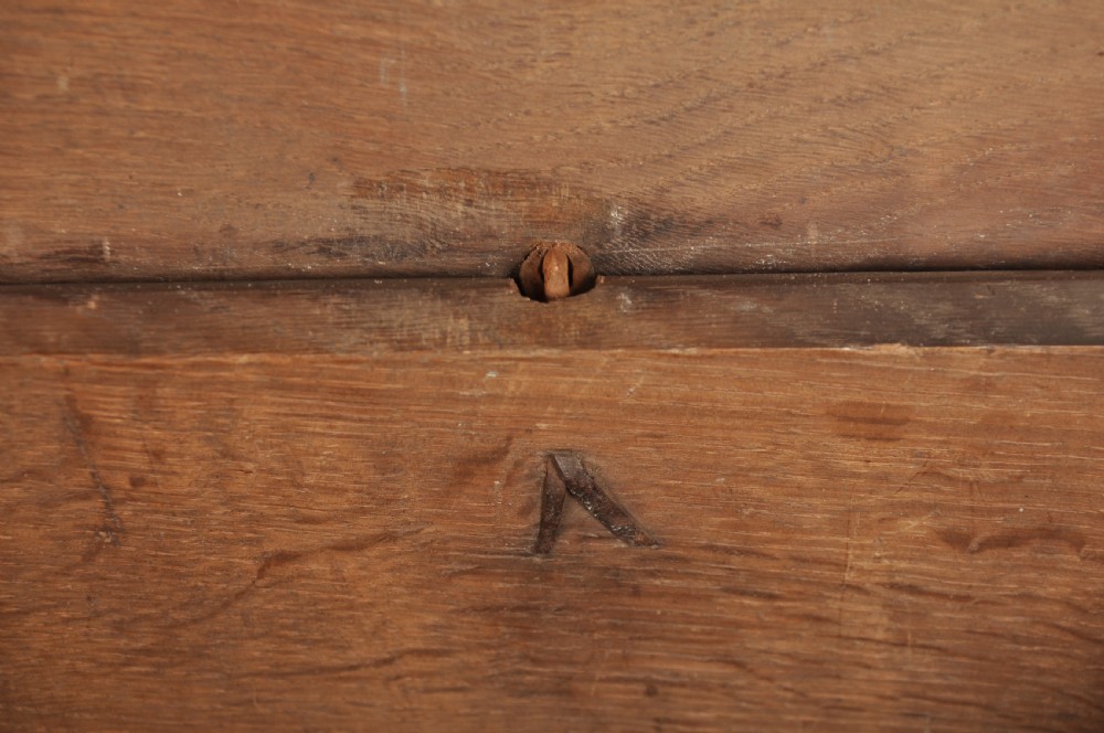 A small 17th century dark oak coffer featuring a flat hinged lid, carved lunette motifs across the front panel, and an iron lock plate. View XII