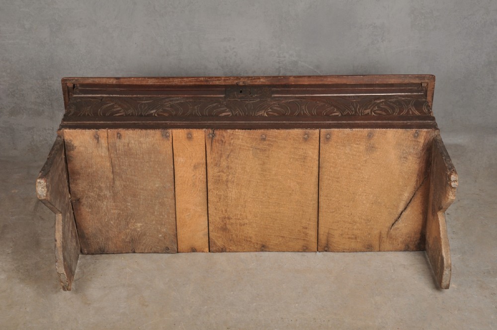 A small 17th century dark oak coffer featuring a flat hinged lid, carved lunette motifs across the front panel, and an iron lock plate. View XIV