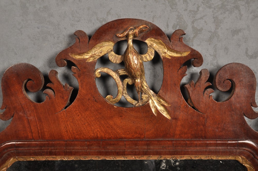 An 18th-century Chippendale style wall mirror featuring a fretwork mahogany frame, a gilded inner moulding, and a gilt phoenix crest at the top. View II