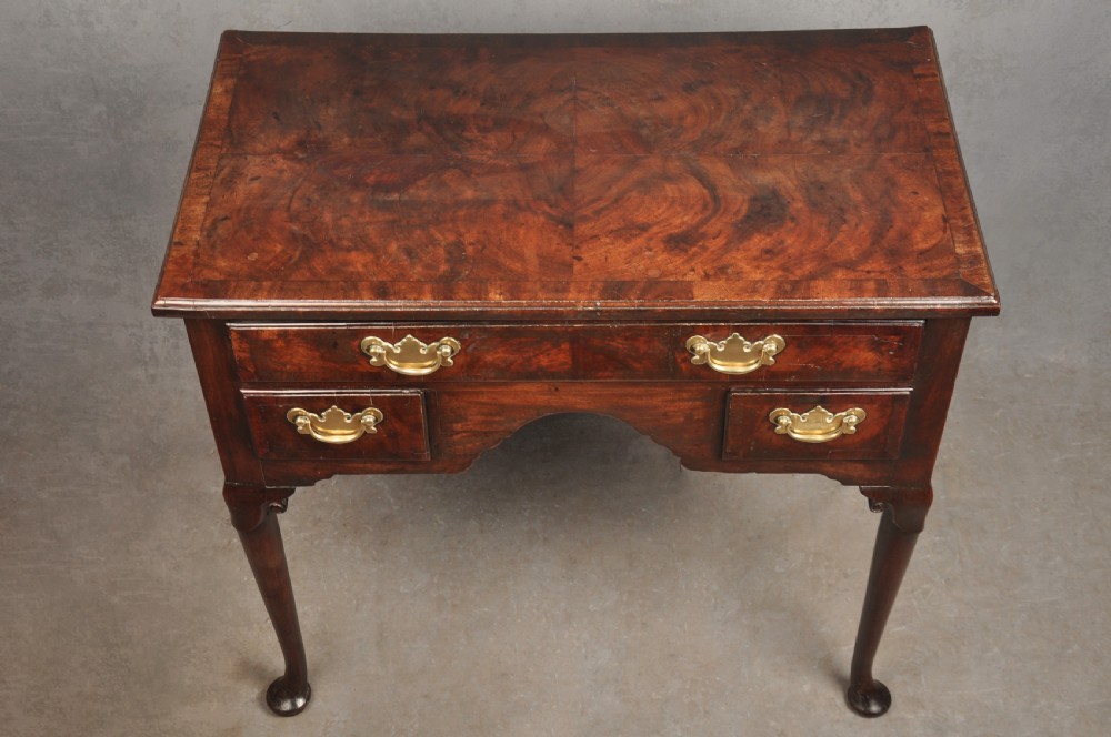 An 18th-century George II mahogany lowboy with three drawers, brass handles, a central arch apron, and four cabriole legs ending in pad feet. View II