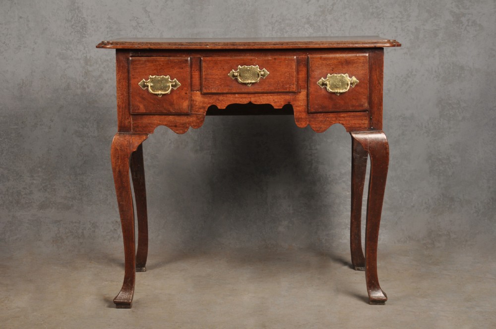 An early 18th-century walnut lowboy side table featuring three drawers with brass handles, a shaped apron, and four cabriole legs. View II