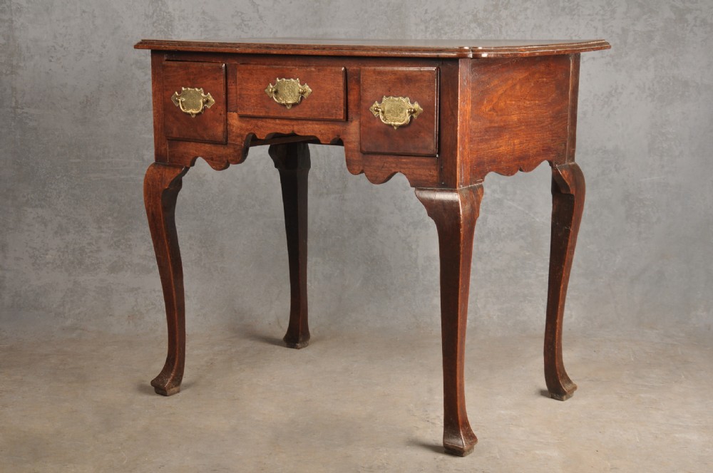 An early 18th-century walnut lowboy side table featuring three drawers with brass handles, a shaped apron, and four cabriole legs. View III