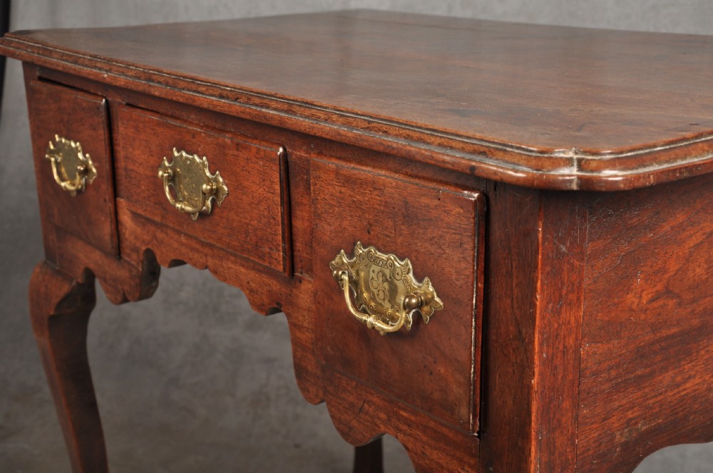 An early 18th-century walnut lowboy side table featuring three drawers with brass handles, a shaped apron, and four cabriole legs. View VII