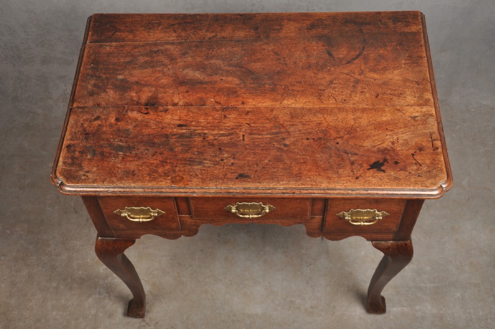 An early 18th-century walnut lowboy side table featuring three drawers with brass handles, a shaped apron, and four cabriole legs. View VIII