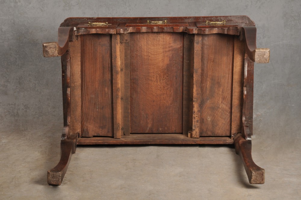An early 18th-century walnut lowboy side table featuring three drawers with brass handles, a shaped apron, and four cabriole legs. View X