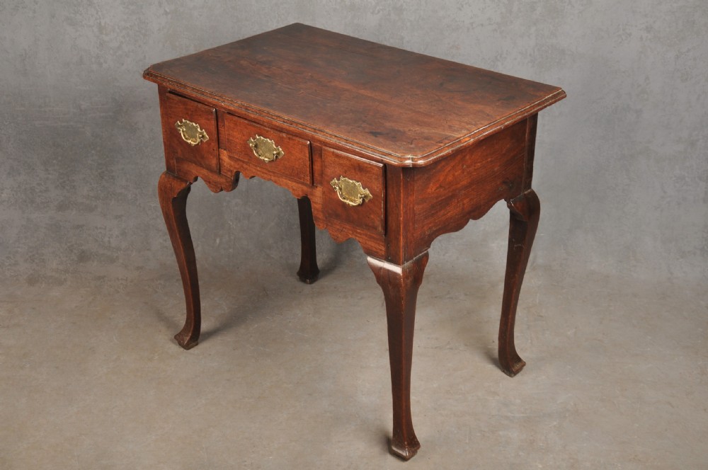 An early 18th-century walnut lowboy side table featuring three drawers with brass handles, a shaped apron, and four cabriole legs. View XII