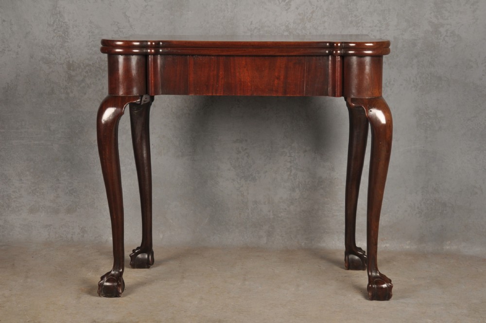 An 18th-century Georgian mahogany fold-over tea table featuring cabriole legs terminating in hand-carved ball and claw feet.