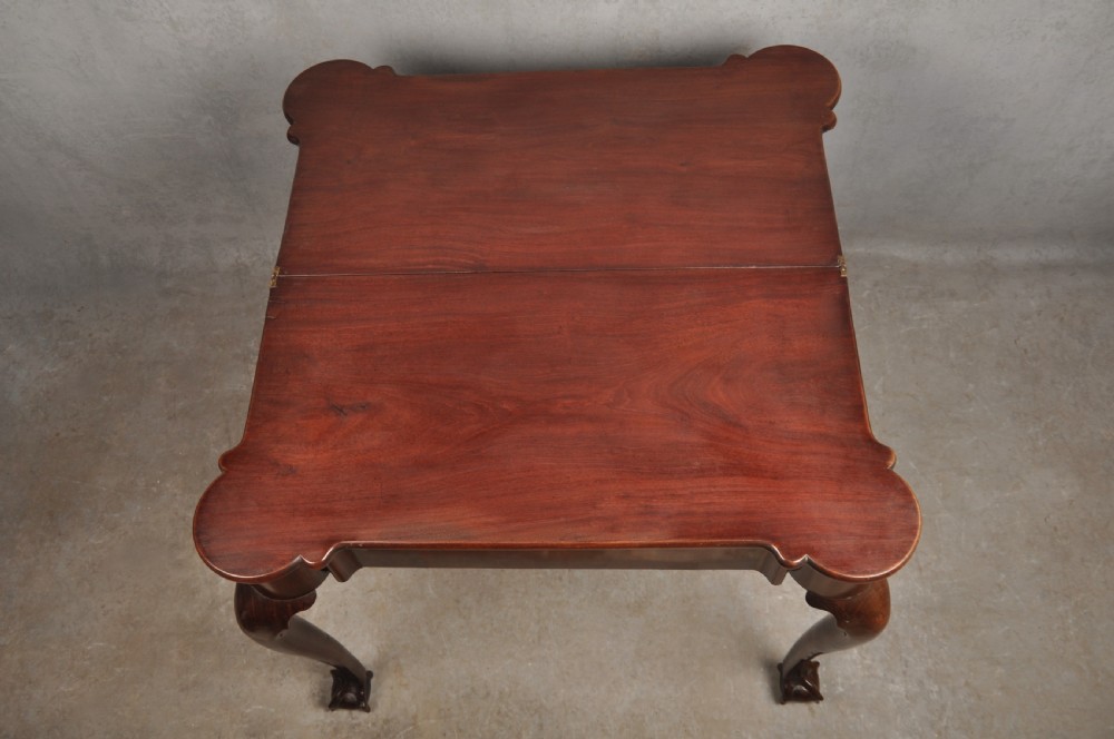 An 18th-century Georgian mahogany fold-over tea table featuring cabriole legs terminating in hand-carved ball and claw feet. View X