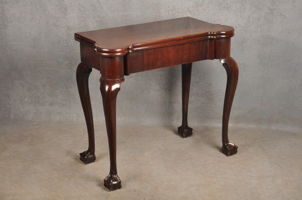 An 18th-century Georgian mahogany fold-over tea table featuring cabriole legs terminating in hand-carved ball and claw feet. View XVIII