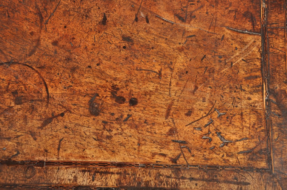 An early 18th-century walnut kneehole desk featuring crossbanded drawer fronts, brass drop handles, a central recessed cupboard, and turned bun feet. View IV