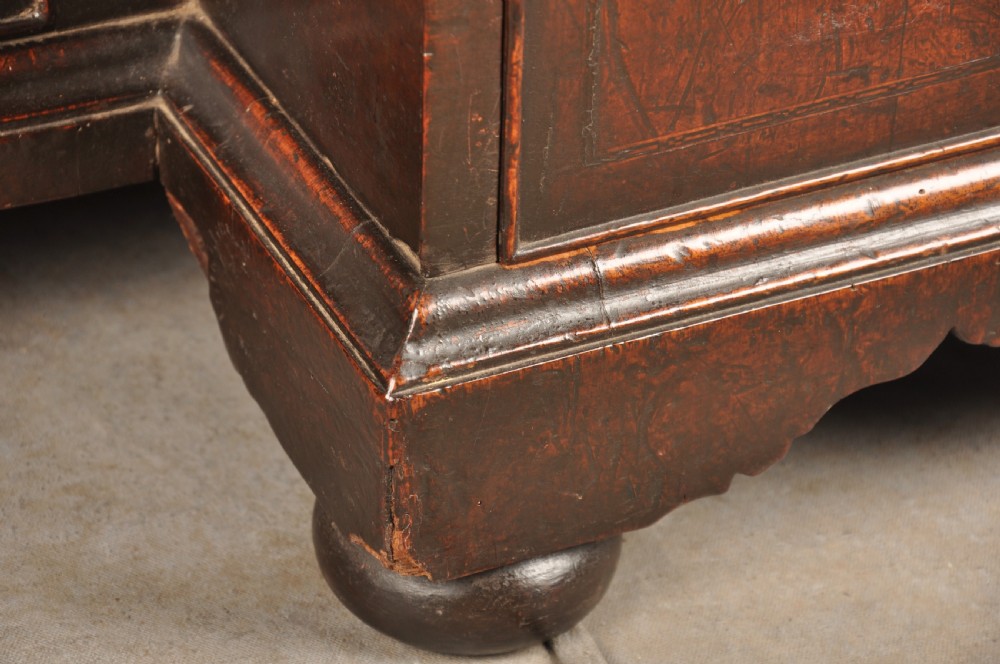 An early 18th-century walnut kneehole desk featuring crossbanded drawer fronts, brass drop handles, a central recessed cupboard, and turned bun feet. View VIII