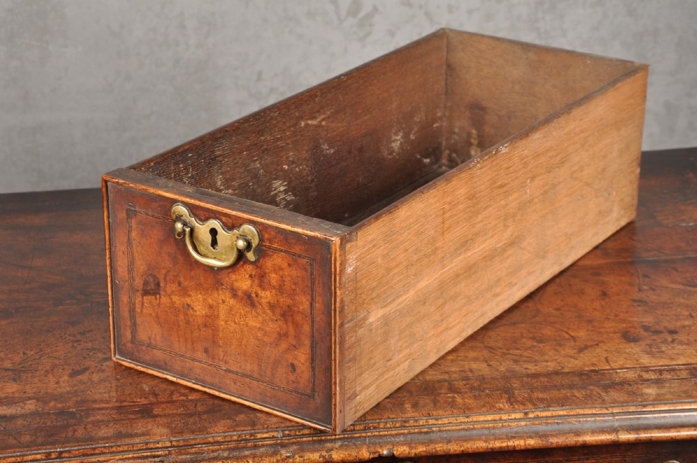 An early 18th-century walnut kneehole desk featuring crossbanded drawer fronts, brass drop handles, a central recessed cupboard, and turned bun feet. View XII
