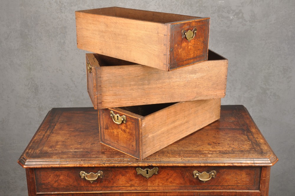 An early 18th-century walnut kneehole desk featuring crossbanded drawer fronts, brass drop handles, a central recessed cupboard, and turned bun feet. View XIII