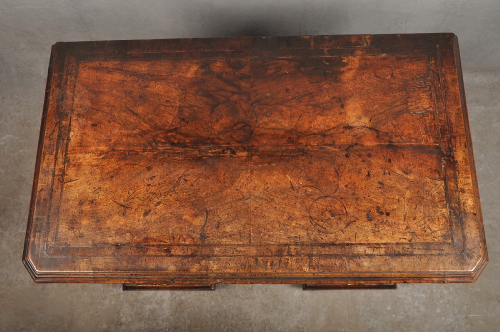 An early 18th-century walnut kneehole desk featuring crossbanded drawer fronts, brass drop handles, a central recessed cupboard, and turned bun feet. View XIV