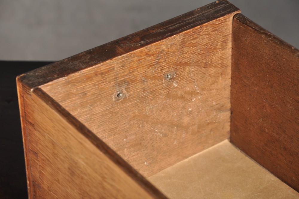 An early 18th-century walnut kneehole desk featuring crossbanded drawer fronts, brass drop handles, a central recessed cupboard, and turned bun feet. View XXI