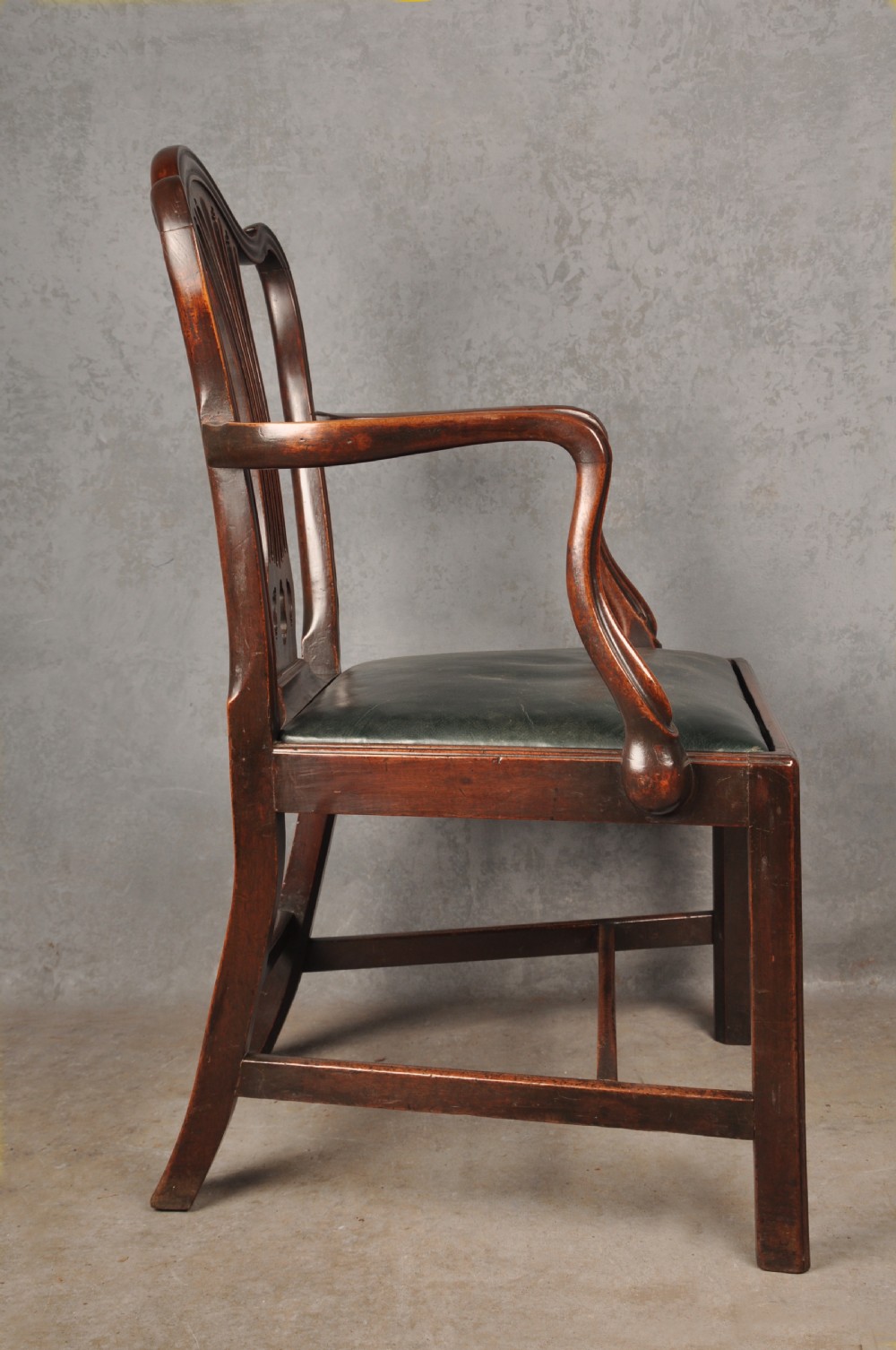 A set of eight 18th-century mahogany Hepplewhite dining chairs featuring pierced splat backrests, serpentine crest rails, square legs with stretchers, and dark green leather drop-in seats. View X