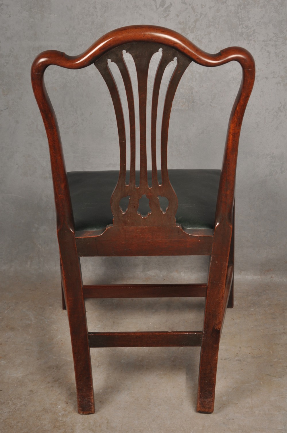 A set of eight 18th-century mahogany Hepplewhite dining chairs featuring pierced splat backrests, serpentine crest rails, square legs with stretchers, and dark green leather drop-in seats. View XIV