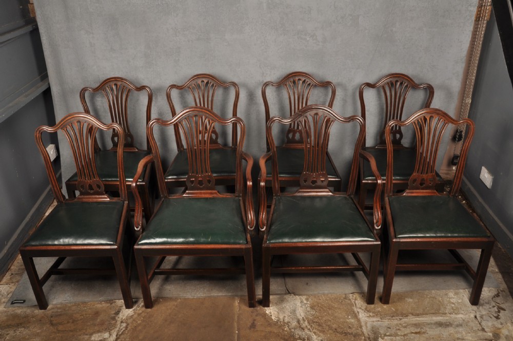 A set of eight 18th-century mahogany Hepplewhite dining chairs featuring pierced splat backrests, serpentine crest rails, square legs with stretchers, and dark green leather drop-in seats. View XVI
