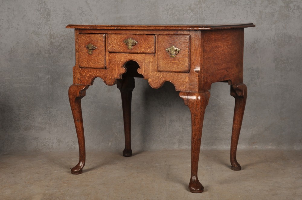 An early eighteenth-century oak lowboy side table featuring three drawers with brass handles, a shaped apron, and four cabriole legs with pad feet. View III