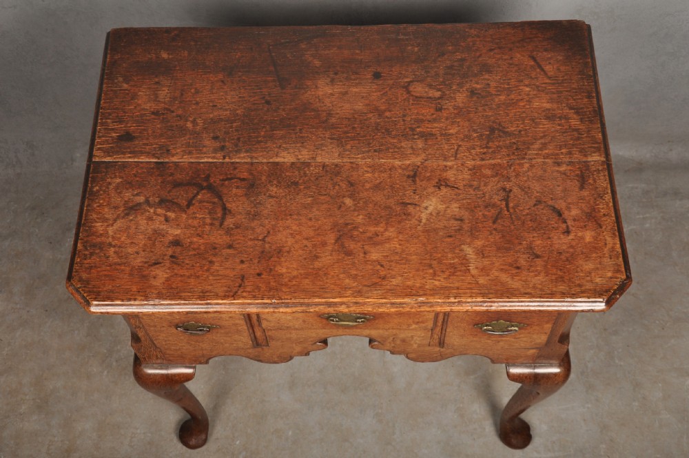 An early eighteenth-century oak lowboy side table featuring three drawers with brass handles, a shaped apron, and four cabriole legs with pad feet. View IV