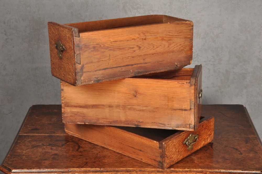 An early eighteenth-century oak lowboy side table featuring three drawers with brass handles, a shaped apron, and four cabriole legs with pad feet. View VI