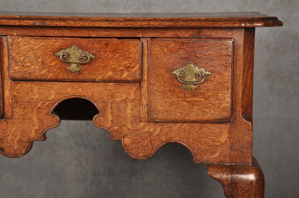 An early eighteenth-century oak lowboy side table featuring three drawers with brass handles, a shaped apron, and four cabriole legs with pad feet. View VII