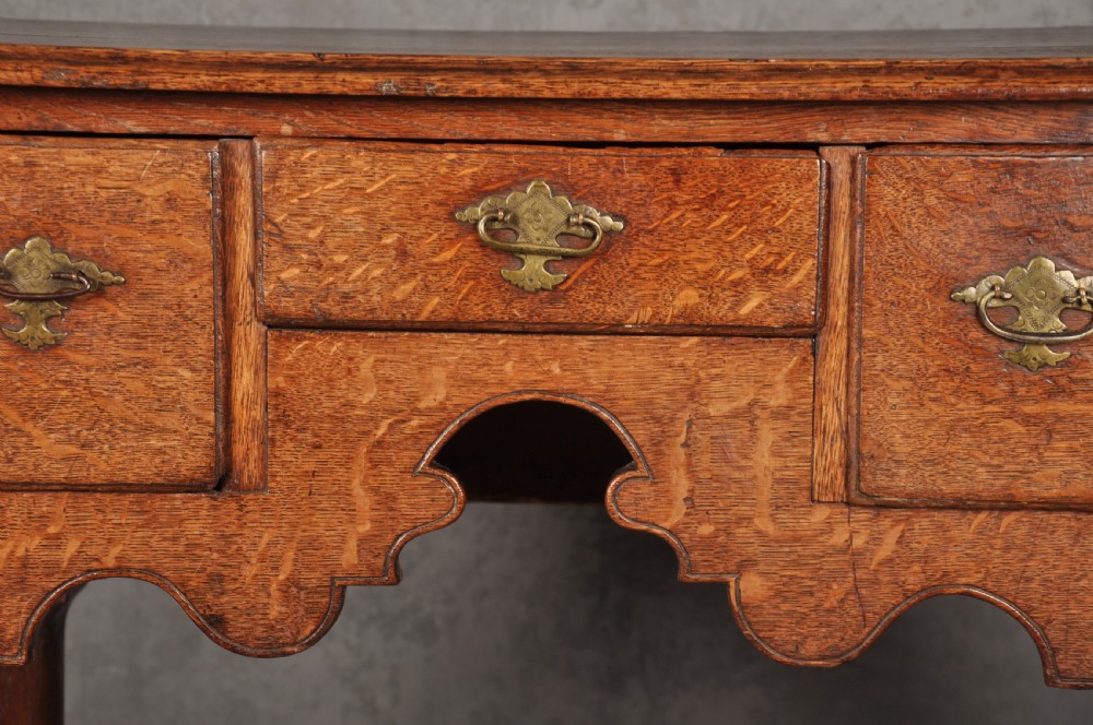 An early eighteenth-century oak lowboy side table featuring three drawers with brass handles, a shaped apron, and four cabriole legs with pad feet. View VIII