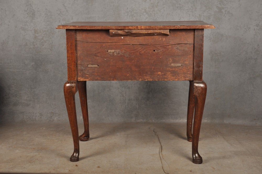 An early eighteenth-century oak lowboy side table featuring three drawers with brass handles, a shaped apron, and four cabriole legs with pad feet. View XII