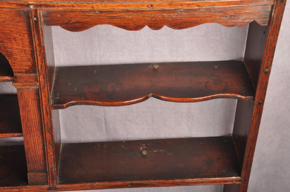 An eighteenth-century dark oak delft rack featuring open shelves, a central arched niche, and a moulded top cornice. View IV