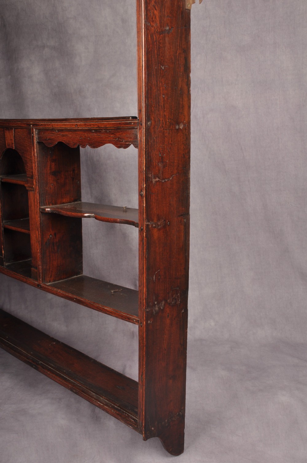 An eighteenth-century dark oak delft rack featuring open shelves, a central arched niche, and a moulded top cornice. View IX
