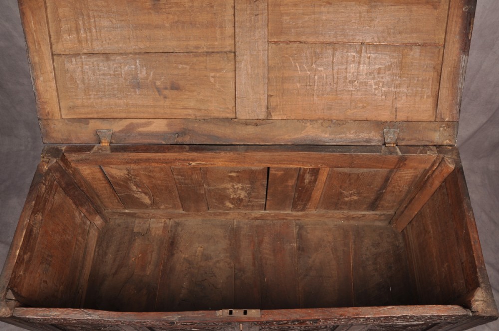 A seventeenth-century dark oak coffer featuring four carved front panels with scroll motifs, a carved top rail dated 1692 with initials DW, and a hinged lid. View XIII