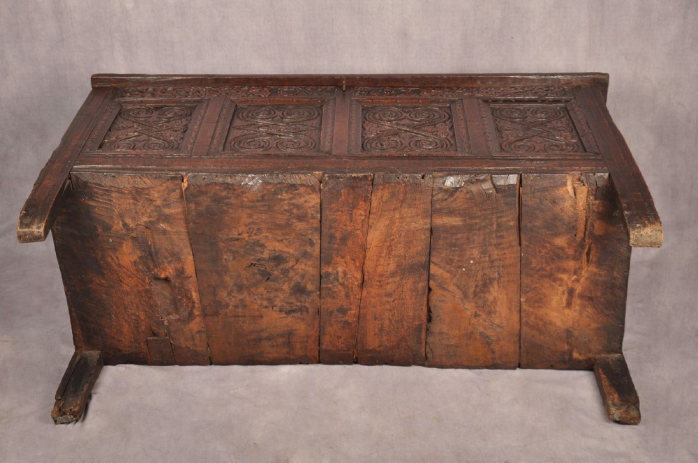 A seventeenth-century dark oak coffer featuring four carved front panels with scroll motifs, a carved top rail dated 1692 with initials DW, and a hinged lid. View XV