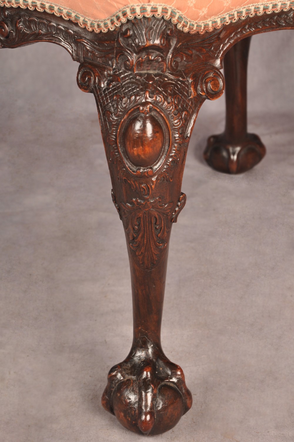 A 19th-century carved walnut stool featuring cabriole legs with claw-and-ball feet and a peach patterned upholstered top. View II