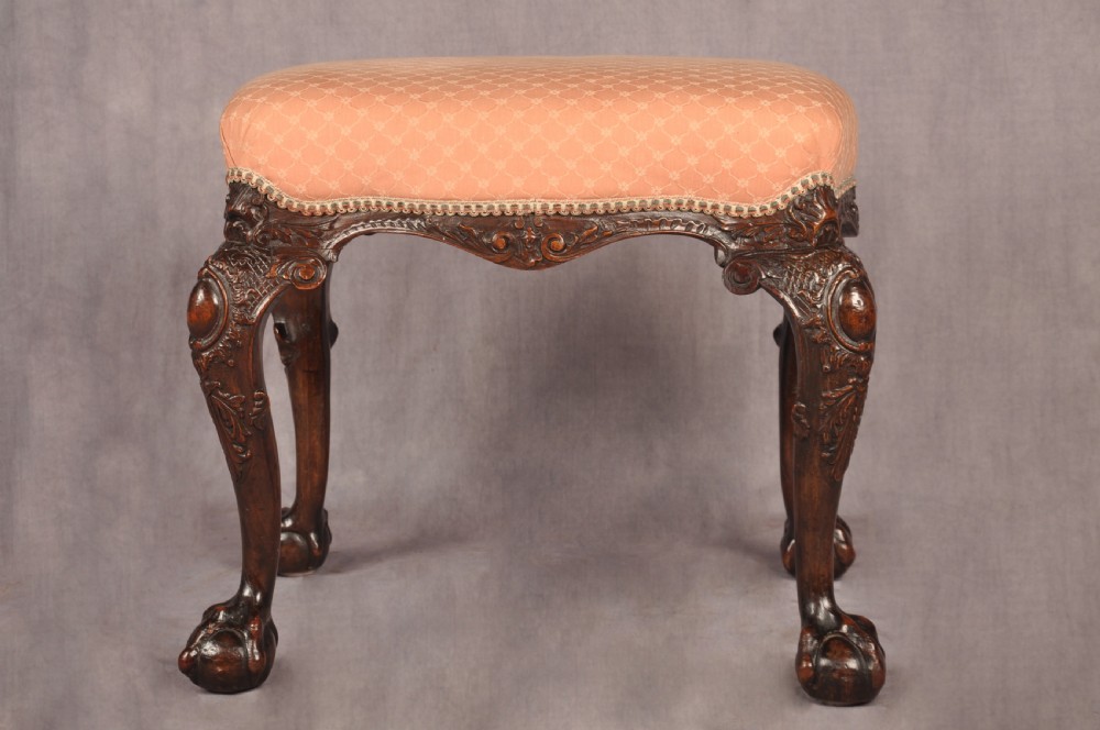 A 19th-century carved walnut stool featuring cabriole legs with claw-and-ball feet and a peach patterned upholstered top. View IV