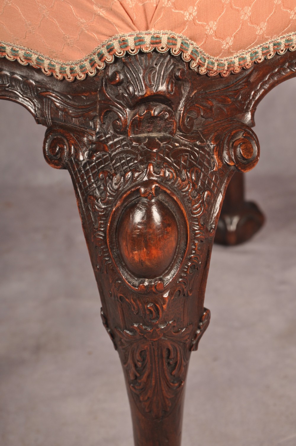 A 19th-century carved walnut stool featuring cabriole legs with claw-and-ball feet and a peach patterned upholstered top. View V