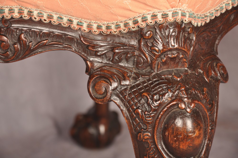 A 19th-century carved walnut stool featuring cabriole legs with claw-and-ball feet and a peach patterned upholstered top. View VI
