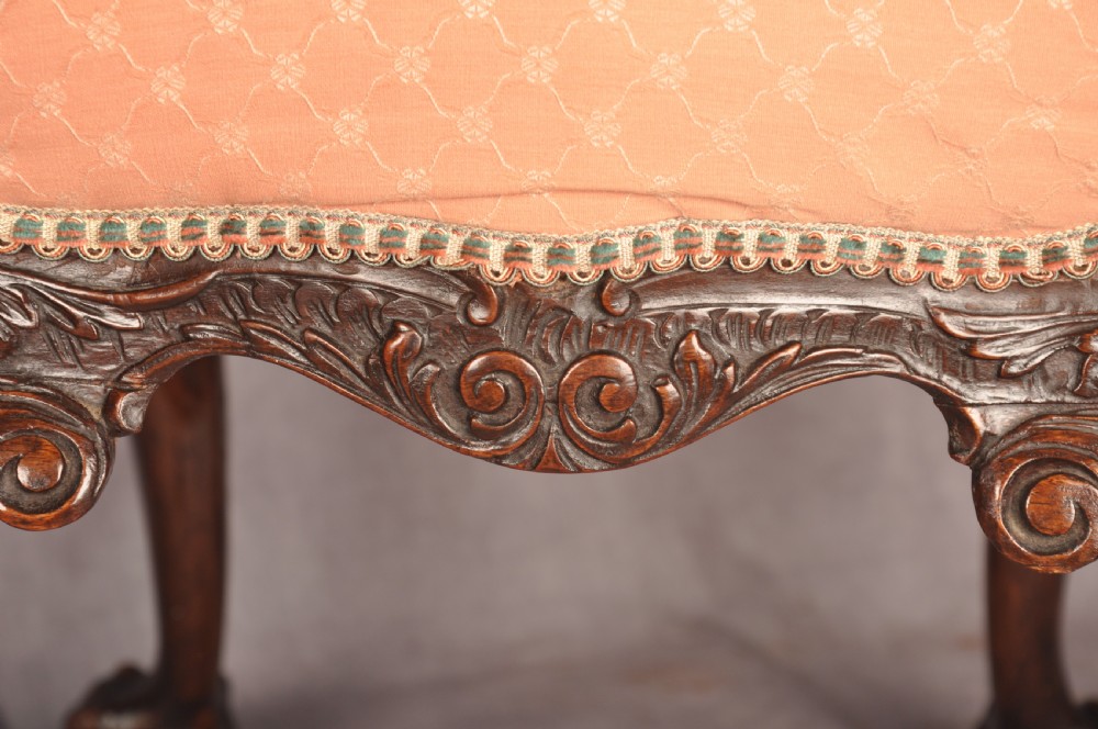 A 19th-century carved walnut stool featuring cabriole legs with claw-and-ball feet and a peach patterned upholstered top. View VII