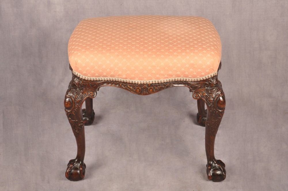 A 19th-century carved walnut stool featuring cabriole legs with claw-and-ball feet and a peach patterned upholstered top. View VIII