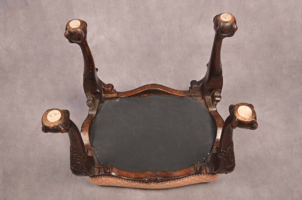 A 19th-century carved walnut stool featuring cabriole legs with claw-and-ball feet and a peach patterned upholstered top. View IX