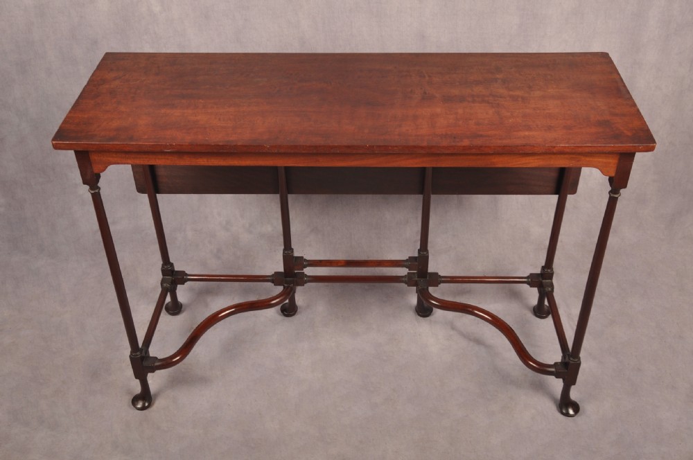 An 18th-century dark mahogany spider leg table featuring slender turned legs, curved stretchers, pad feet, and a drop-leaf top.