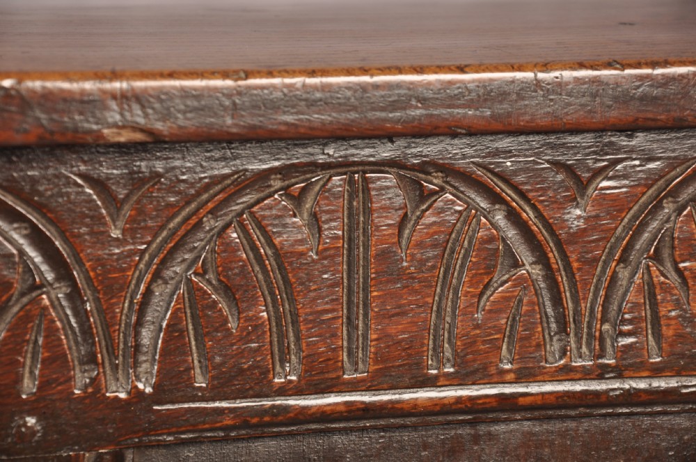 A dark oak 17th century coffer featuring carved lozenge motifs across three front panels beneath an arcaded frieze and iron lockplate. View IV